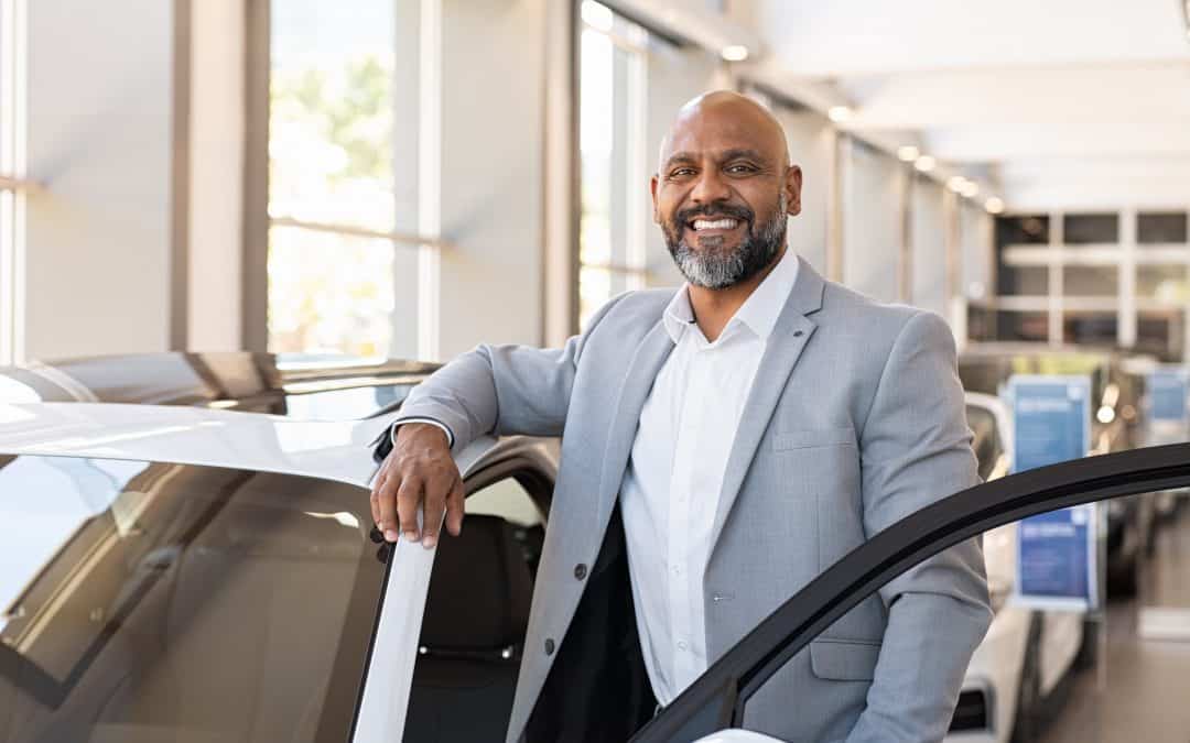 Happy man getting in to car while inside a dealership or structure.