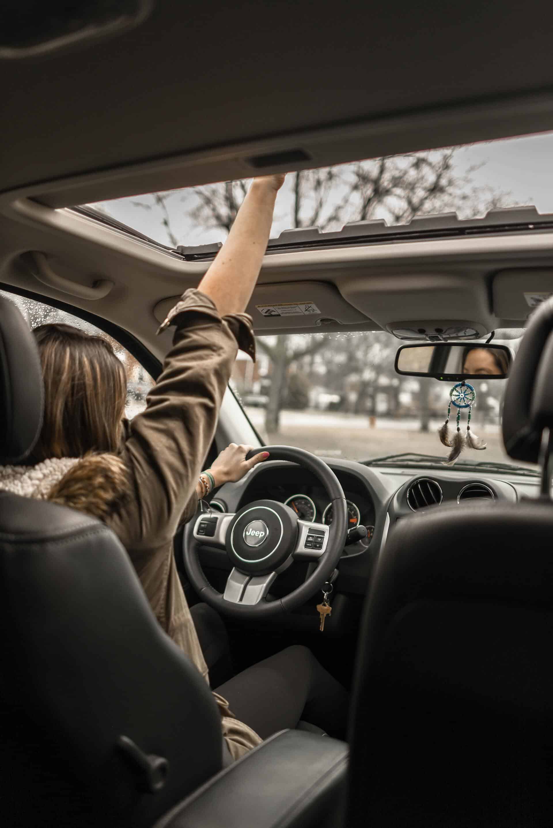 Woman super happy while driving a car because she is in a car she likes.