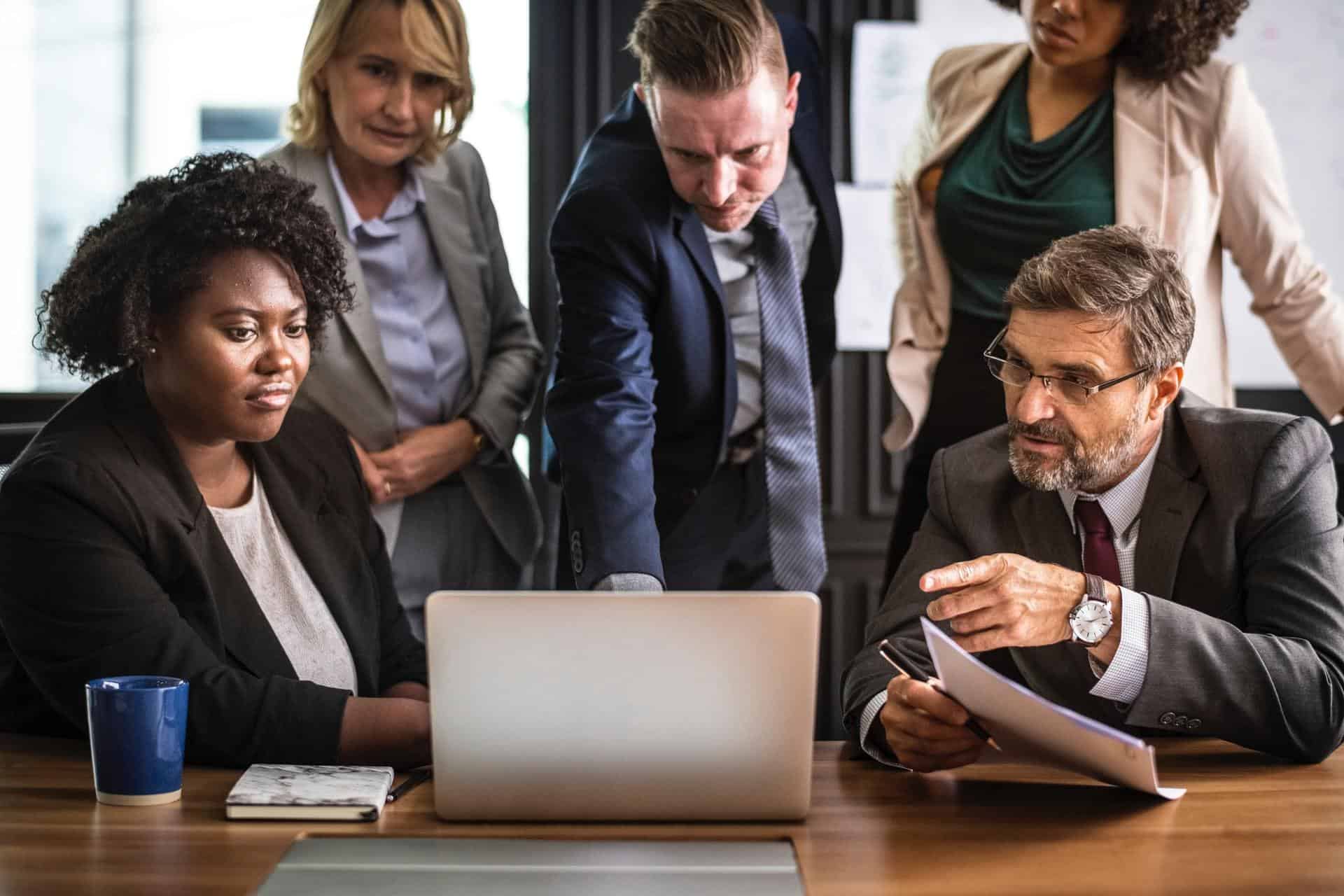 A group of business people scrutinizing something on a laptop.