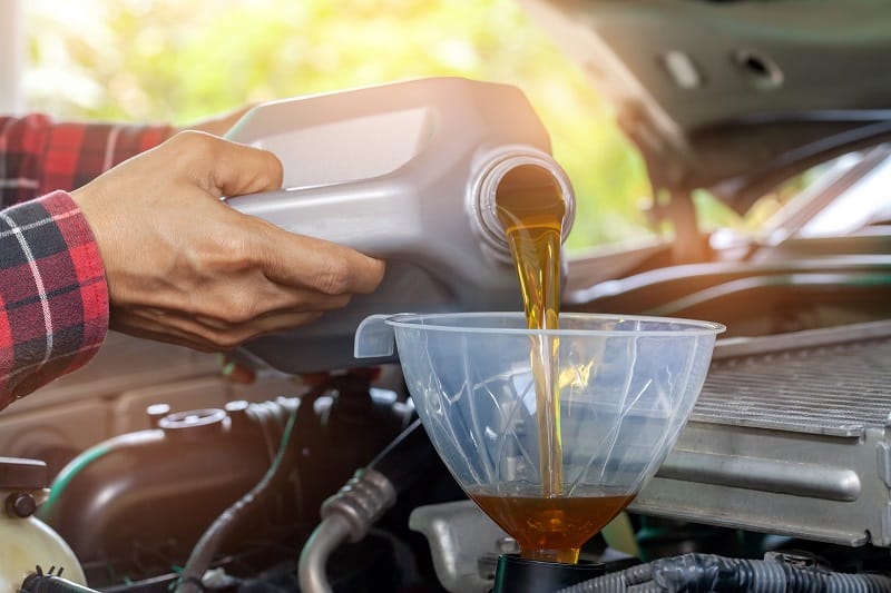 Car maintenance servicing mechanic pouring new oil lubricant into the car engine.selective focus.